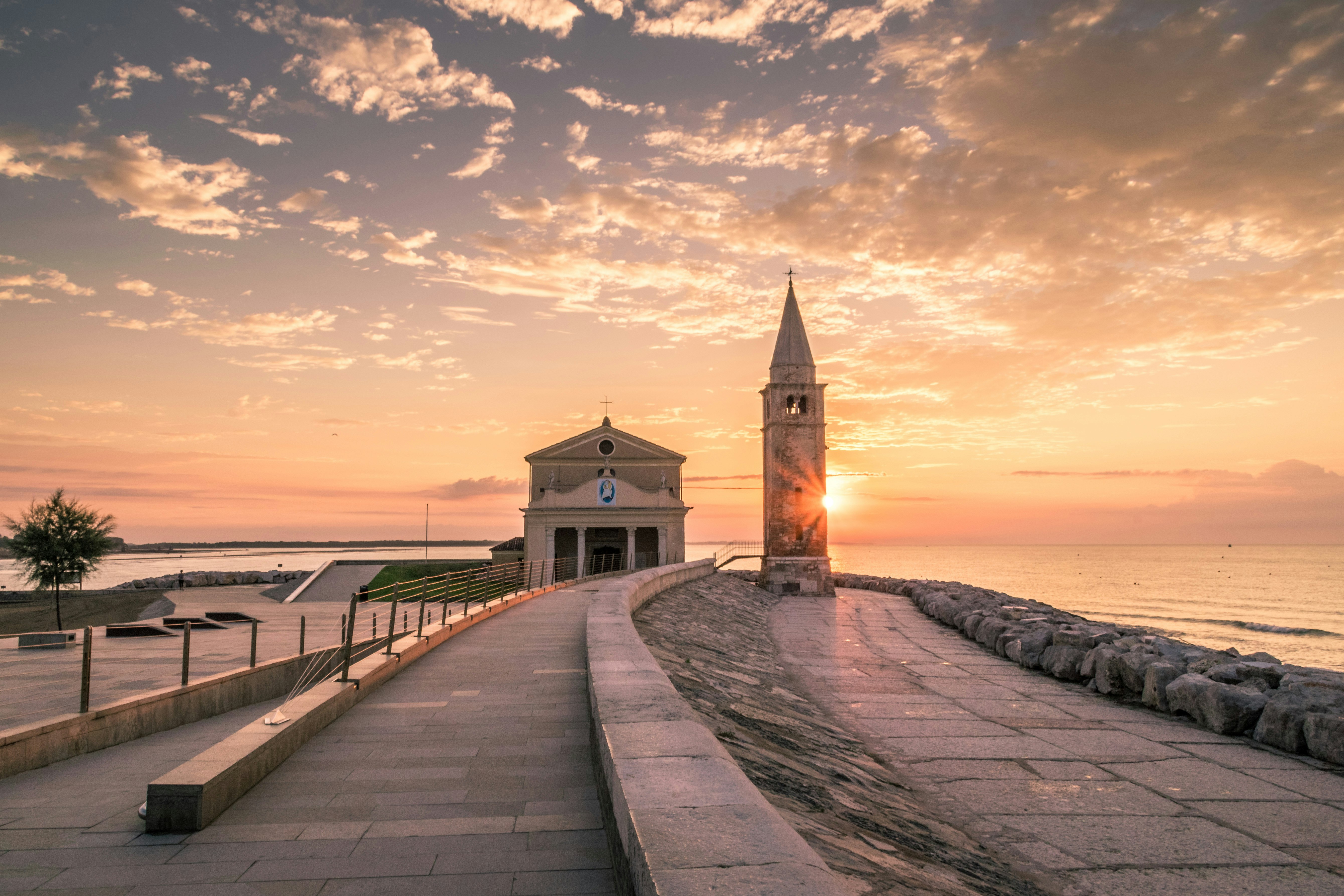 white building beside tower during sunset